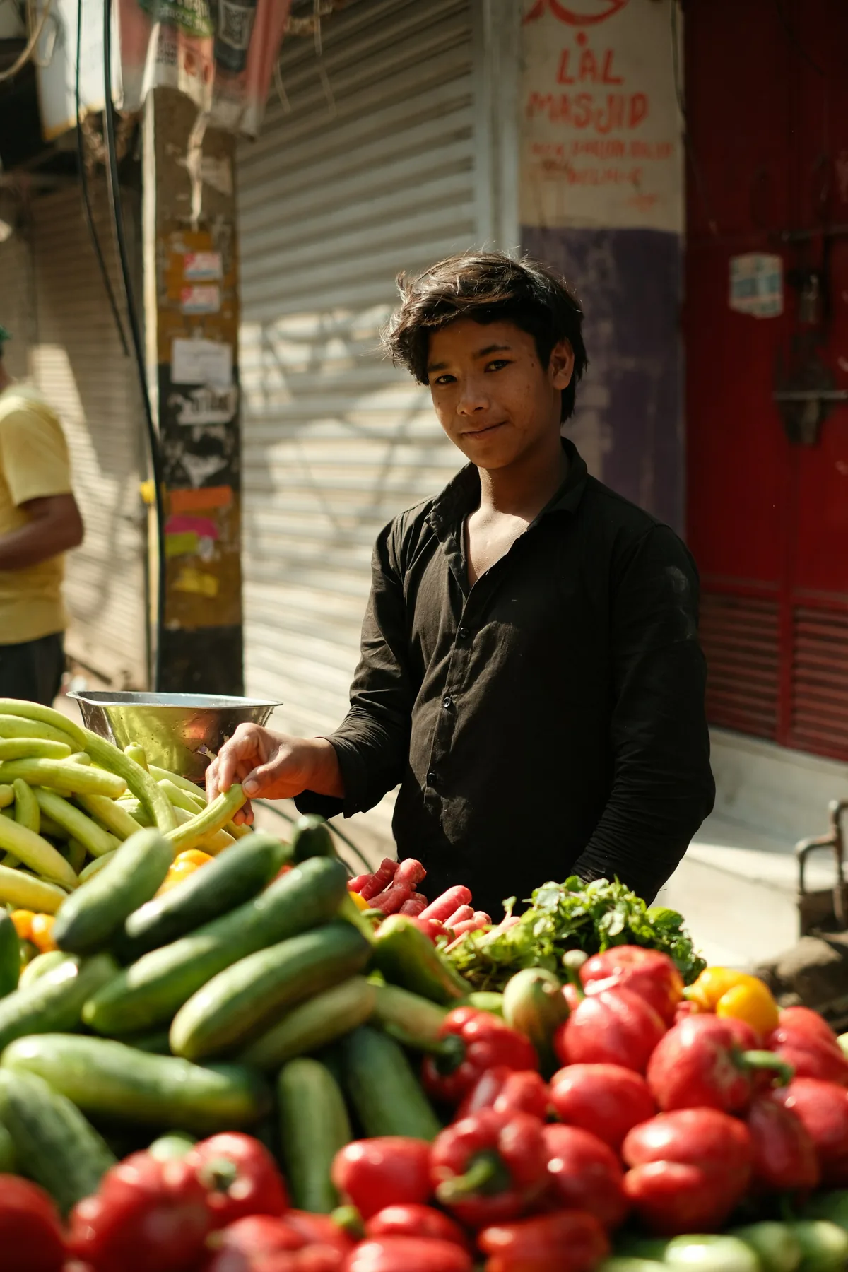 A market worker stands behind a display of fresh produce.