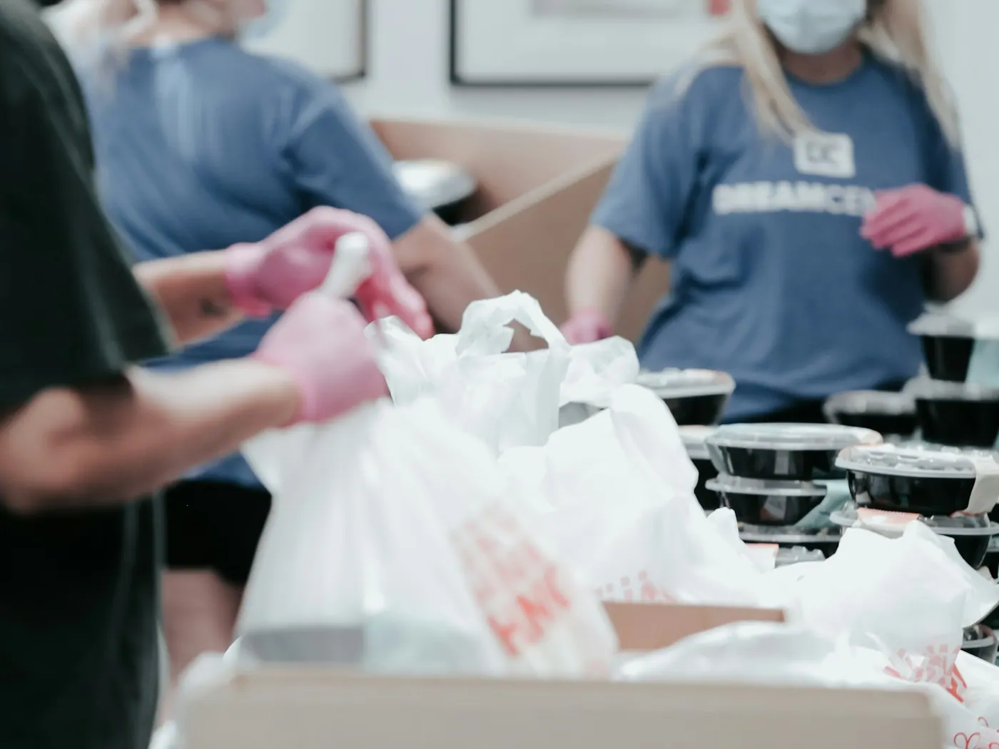 Volunteers work together to pack prepared food.